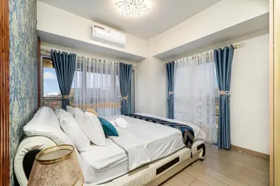 a bedroom with a bed with blue curtains and a window at Luxurious Staycation near Okada, Airport, City of Dreams, Solaire, and MOA with free pool & gym in Manila