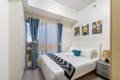 a bedroom with a white bed and a window at Luxurious Staycation near Okada, Airport, City of Dreams, Solaire, and MOA with free pool & gym in Manila