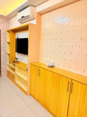 a room with wooden cabinets and a tv on a wall at Shell Residences Prime By Paul in Manila
