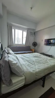 a large bed in a bedroom with a window at Quantum Residences in Manila