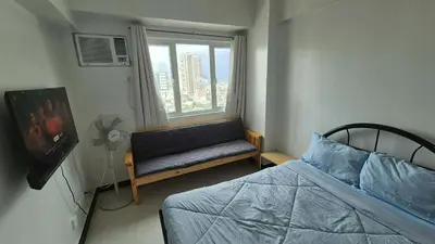 a bedroom with a bed and a window with a bench at Quantum Residences in Manila