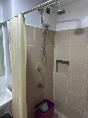 a bathroom with a shower with a curtain and a sink at Quantum Residences in Manila