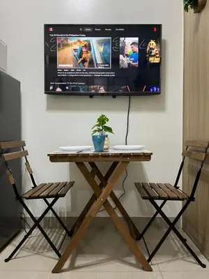a wooden table with two chairs and a tv on a wall at Athara Suites 2 in Manila