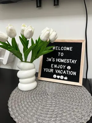 a vase with white flowers on a table with a sign at 3Ms Homestay Shore in Manila
