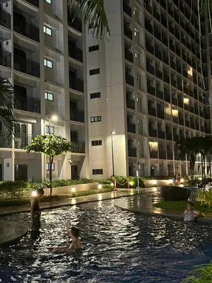 a group of people swimming in a pool in front of a building at 3Ms Homestay Shore in Manila