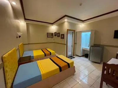 a bedroom with two beds and a television in it at Palette Gems Hotel and Conference Center in Quezon City
