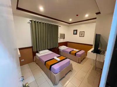 a hotel room with two beds and a television at Palette Gems Hotel and Conference Center in Quezon City