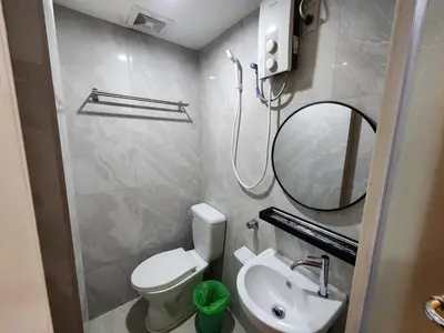 a bathroom with a toilet and a sink and a mirror at Stone House Hotel Manila in Manila