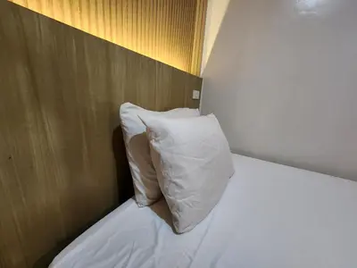 a bed with a white pillow and a wooden headboard at Stone House Hotel Manila in Manila