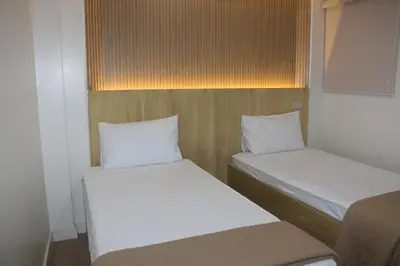 two beds in a small room with white sheets at Stone House Hotel Manila in Manila
