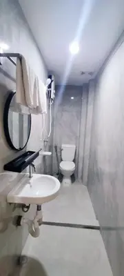 a bathroom with a sink and a toilet and a mirror at Stone House Hotel Manila in Manila