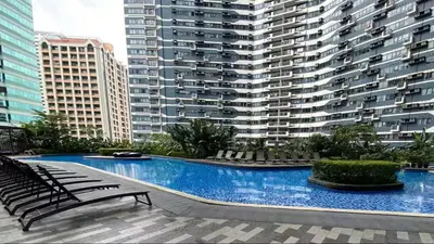 a swimming pool with chairs and large buildings at Air Residences 49F City View, Wifi & Netflix in Manila