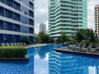 a swimming pool with chairs and a building at Stylish 1BR Air Residences Wifi & Netflix in Manila