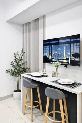 a kitchen with a bar with two stools and a tv at Park Mckinley West Luxury 1Br Suite in Manila