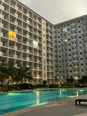 a large apartment building with a swimming pool at night at Feel at Home in Manila