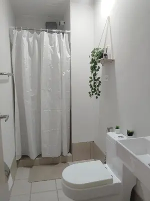 a white bathroom with a toilet and a shower at Feel at Home in Manila