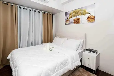 a bedroom with a white bed and a window at Snooze & Stay in Manila