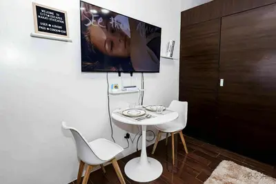 a room with a white table and chairs and a tv at Snooze & Stay in Manila