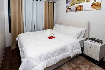 a bedroom with a white bed with a red box on it at Snooze & Stay in Manila
