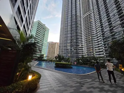 two men standing next to a swimming pool in a city at Mafresco Makati Staycation in Manila