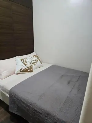 a bed in a room with a white wall at Mafresco Makati Staycation in Manila