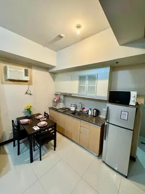 a small kitchen with a table and a refrigerator at J&A CondoStay Near NAIA Terminal 3 in Manila