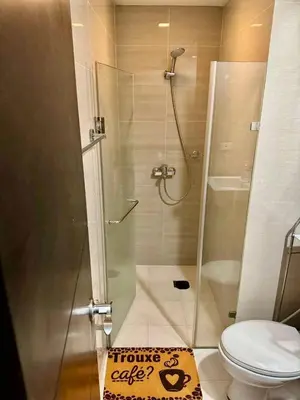 a bathroom with a shower with a toilet and a sign at J&A CondoStay Near NAIA Terminal 3 in Manila