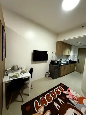 a living room with a table and a kitchen at Wonder Collective Stays in Manila