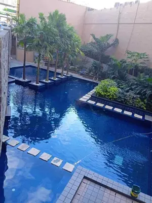 a large pool with palm trees in a building at Staycation by Capri in Manila