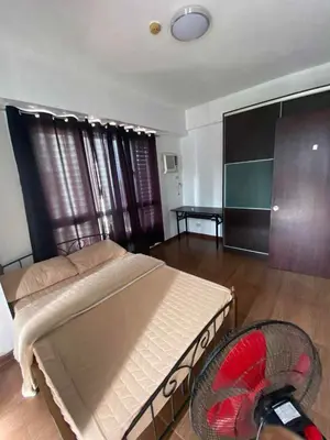 a bedroom with a large bed and a fan at Staycation by Capri in Manila