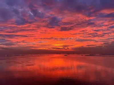 a sunset on the beach with the reflection in the water at Seaview 2BR CondoteI Near Airport,NAIA, MOA ,Okada Casino in Manila