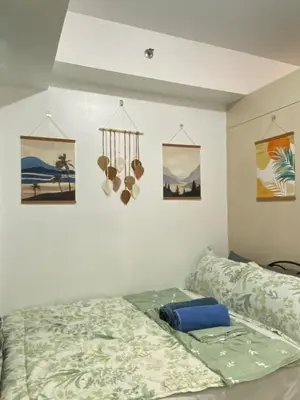 a bedroom with a bed and some pictures on the wall at Stern Staycation Moa Sea Residences in Manila