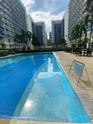 a large blue swimming pool with buildings in the background at Stern Staycation Moa Sea Residences in Manila