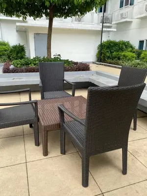 three wicker chairs and a table and a table and chairs at Stern Staycation Moa Sea Residences in Manila