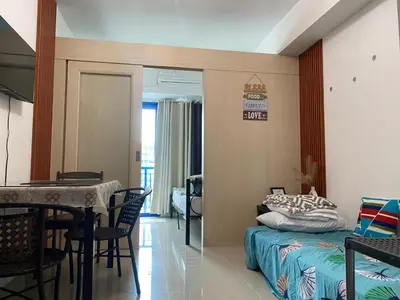 a room with a bed and a table and a dining room at Stern Staycation Moa Sea Residences in Manila