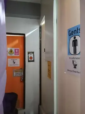 a bathroom with a door and a sign on the wall at SL Bedspace Transient House in Manila