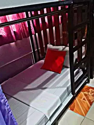 a small bed with a red pillow on it at SL Bedspace Transient House in Manila