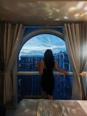 a woman looking out of a window at a city at Self check-in Spacious 1BR near Airport NAIA T3, Mall of Asia in Manila