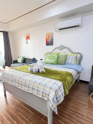 a bedroom with a bed with green and blue pillows at Sy bay suites Near Ayala mall PITX DFA T3T2 Okada MSV2106 in Manila