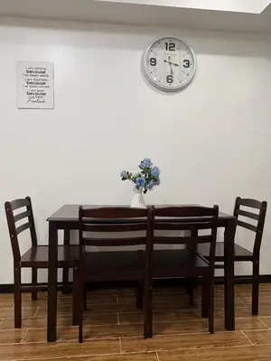 a dining room table with two chairs and a clock on the wall at Sy bay suites near PITX NAIA Airport T3 MOA Okada MSV2107 in Manila