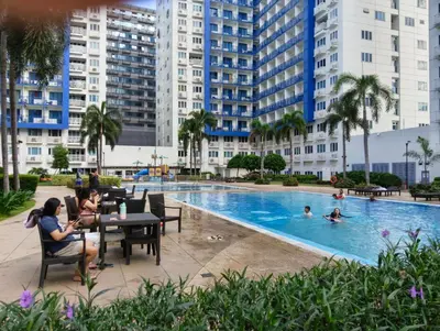a group of people sitting at a table by a swimming pool at Queen Pia Condotel in Manila