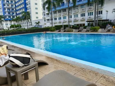 a pool at a hotel with a chair and a hat at Queen Pia Condotel in Manila