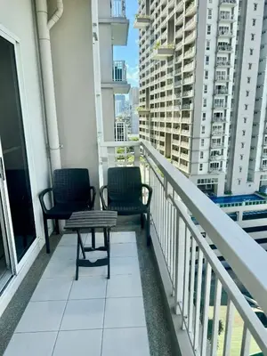 two chairs and a table on a balcony with buildings at Vacation at Munti in Manila