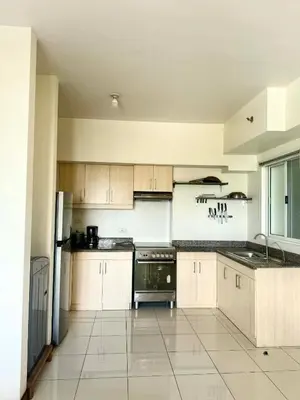 a large kitchen with white cabinets and a refrigerator at Vacation at Munti in Manila