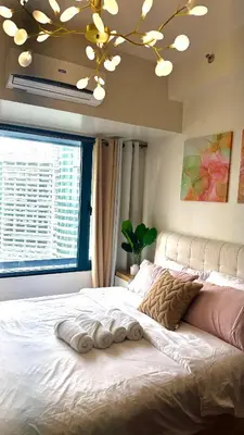 a bedroom with a large bed with a large window at Snooze & Stay in Manila