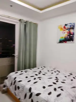 a bedroom with a black and white bed and a window at Birch tower Condominium in Manila