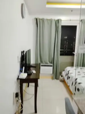 a bedroom with a desk and a bed and a window at Birch tower Condominium in Manila