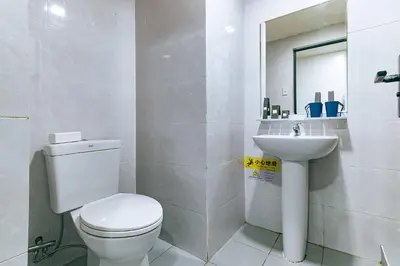 a white bathroom with a toilet and a sink at Luna Hotel by RedDoorz near MOA in Manila