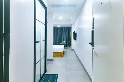 a corridor of a room with a bed and a window at Luna Hotel by RedDoorz near MOA in Manila