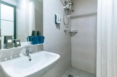 a white bathroom with a sink and a shower at Luna Hotel by RedDoorz near MOA in Manila
